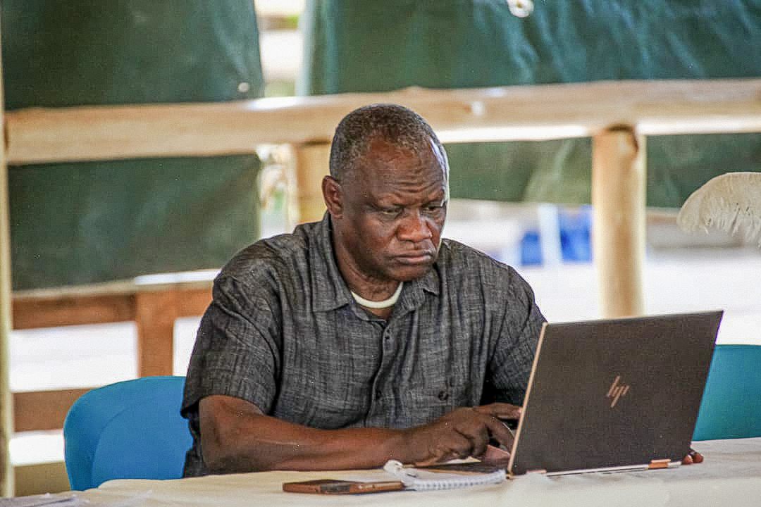 Hon. David Bwangamoe Pulkol working on a laptop during a festival dialogue session